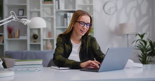 Successful young business lady wearing glasses using laptop smiling while working sitting workplace