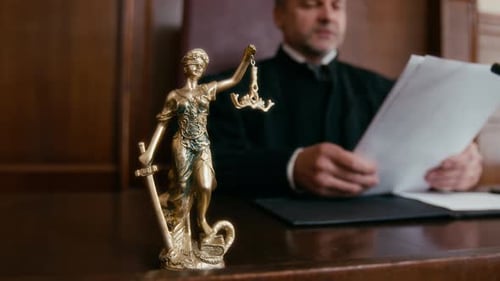 Close-up of Golden Statue of Lady Justice at Table of Judge in Courtroom