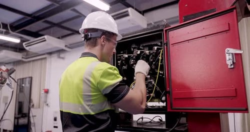 male technician performs slowmotion maintenance on industrial electrical cabinet inside smart