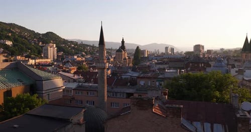 Sunset View Of Sarajevo's Skyline With Mosque Minaret, Orthodox Cathedral Dome, And Surrounding