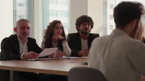 A Group of People in Business Suits are Sitting at a Large Table in the Office and Discussing