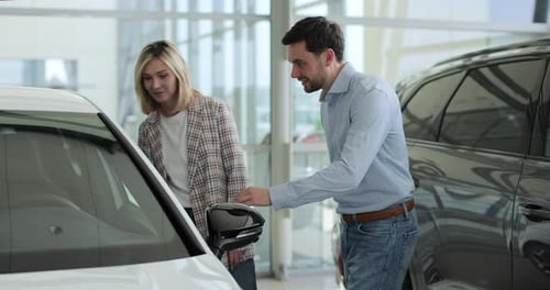 Attractive Young Couple Discussing Chosen Auto in Automobile Showroom Concept of Car Shopping Buying