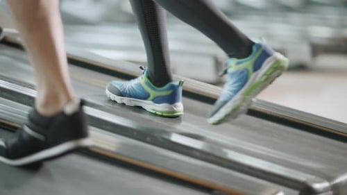 Closeup Two Pair of Feet Moving on Treadmill in Fitness Gym. Fit