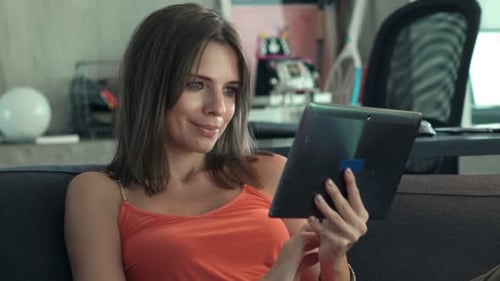 Woman Relaxing on Sofa Using Tablet Device