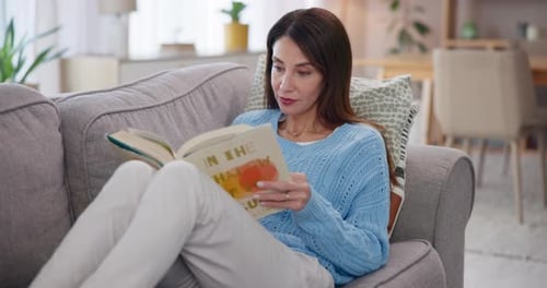 Woman Relaxing Reading Book on Couch at Home