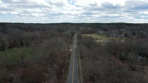 Aerial tracking shot of a motorcyclist driving down country road. Slow motion drone follow