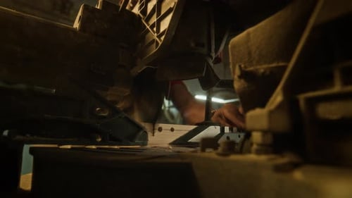 Chop Saw Cutting Wood in Dimly Lit Workshop