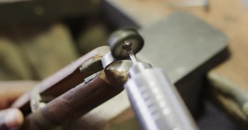 Biracial female worker shaping ring using handcraft tools in workshop in slow motion