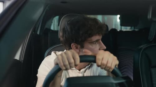 Distressed Young Man in Car with Head on Wheel