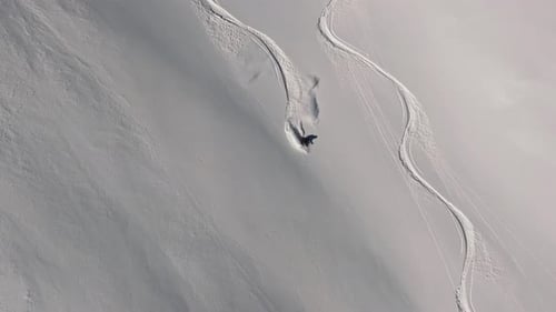 Skier Carving Down Snowy Mountain Slope on Sunny Day