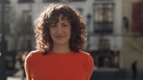 Attractive Curly Female Model Looking At Camera In Public Town Square