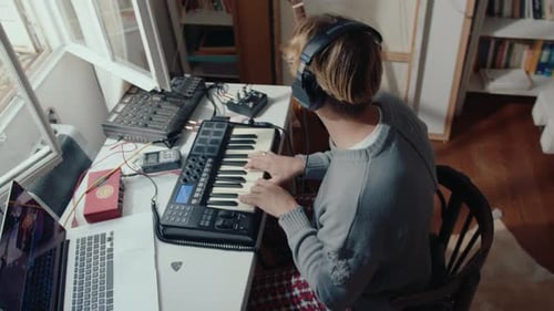 Musician in Headphones Playing Synthesizer at Home Recording Studio