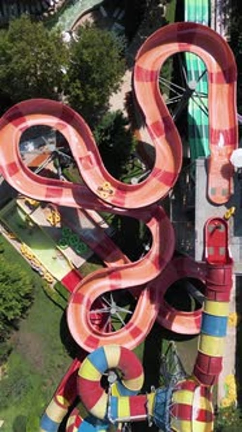 Aerial View of Colorful Twisting Water Slides with People Riding Inflatable Tubes at a Water Park