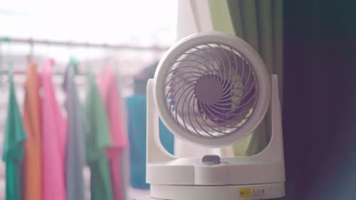 Mini Portable Electric Fan In White And Purple Color Rotating Inside A Room In The House With Clothe