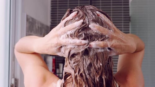 Close Rear View of Hands Massaging Shampoo Into Wet Hair Creating Foam, Focus on Texture and Movemen