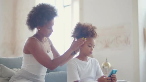 Young Adult Brushing Child's Hair Indoors