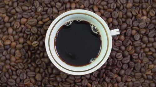 Coffee Cup Surrounded by Coffee Beans Overhead Shot