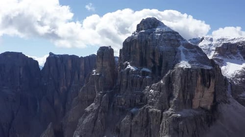 Drone flying close to spectacular mountain peak with snow covered top of Dolomites, Italian alps