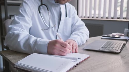 Concentrated Professional Young Doctor and Uniform is Working in His Office Doing Paperwork