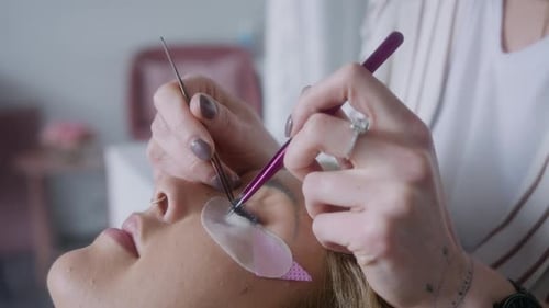 Visão aproximada de um profissional aplicando extensões de cílios