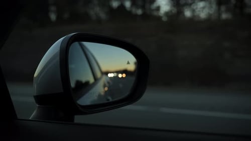 Blur Reflection in the Side Mirror of Driving Car on the Road on Evening Time View From Front
