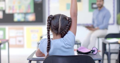 Biracial girl raises her hand in a classroom at school
