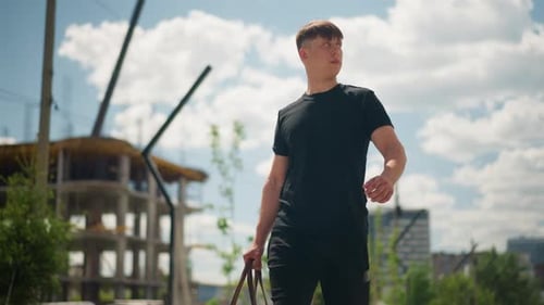 Male Figure Walking Near Building Site with Carrying Bag Confidence Man Strides Past Urban