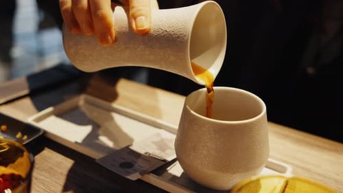 Pouring Drink into Textured Cup at Cafe Table