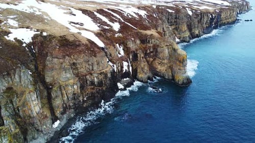 Flying Over Rocky Coastline Alongside Cliffside with Blue North Atlantic Ocean Water at Spring
