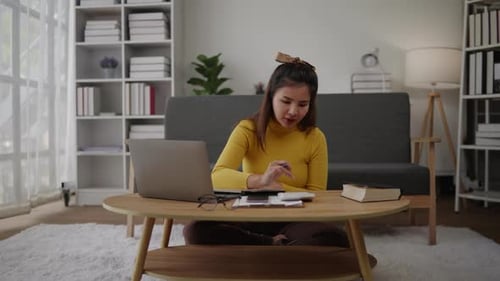 Woman working on laptop and calculator at home