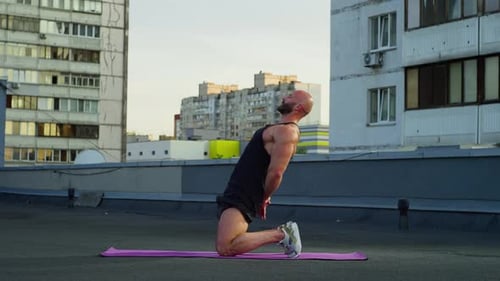 Muscular Man Doing Back Bend Exercise on Rooftop