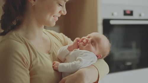 Loving Mother Holding Sleeping Infant Child at Home
