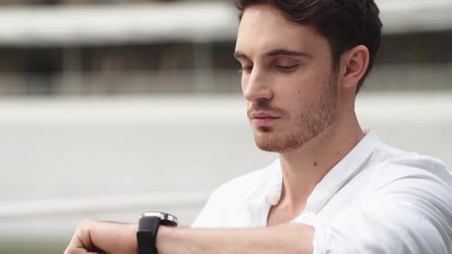 Man Checking Smartwatch Outdoors in Daylight