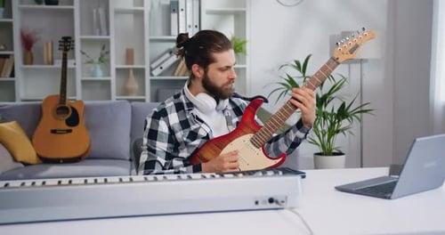 Man Playing Electric Guitar in Home Music Studio