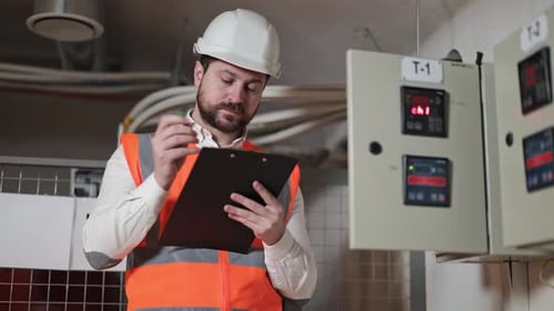 Electrical Engineer Inspects Control Panel in Industrial Building
