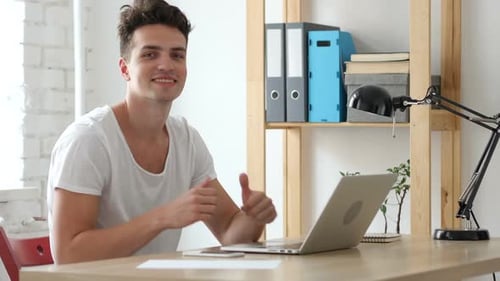 Thumbs Up By Creative Young Man Working in Office