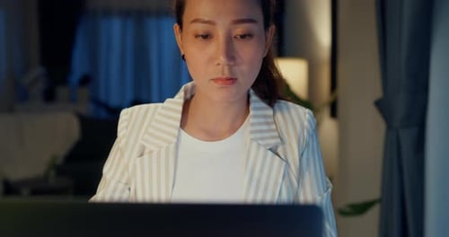 Woman Working on Laptop at Home at Night
