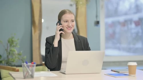 Young Woman Talking on Phone at Desk