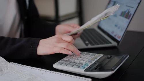 Woman Checking Bills Taxes Bank Account Balance and Calculating Expenses in the Living Room at Home