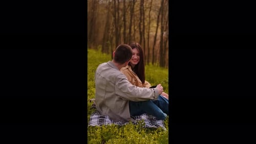 A young couple sits by the lake, enjoying the beautiful scenery. Camping in nature, representing tee
