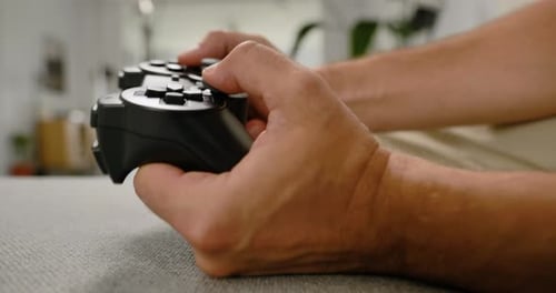 Close-up of hands playing video games at home