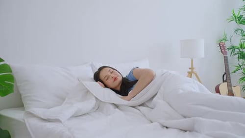 Young Woman Sleeping Soundly in Bright White Bedroom