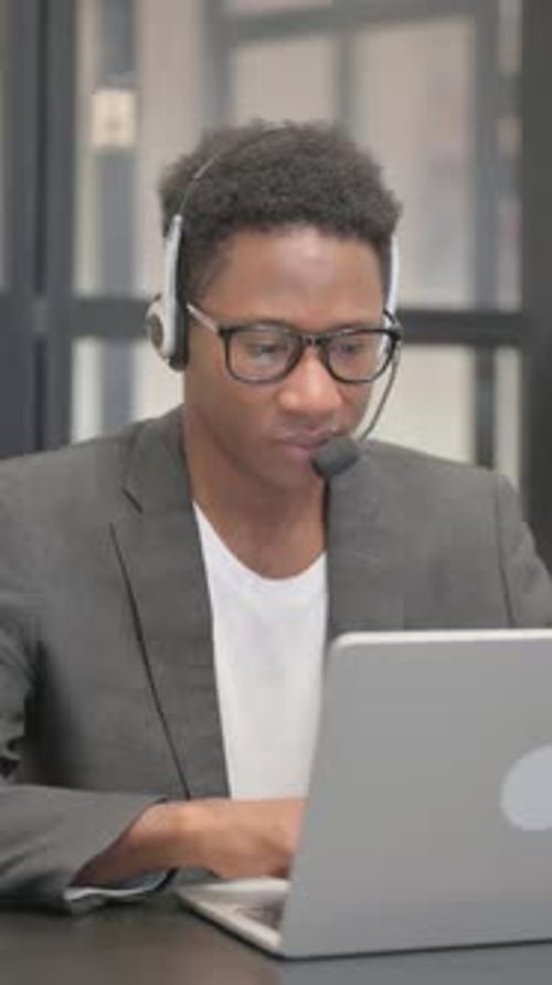 Man with Headset Working on Laptop in Office