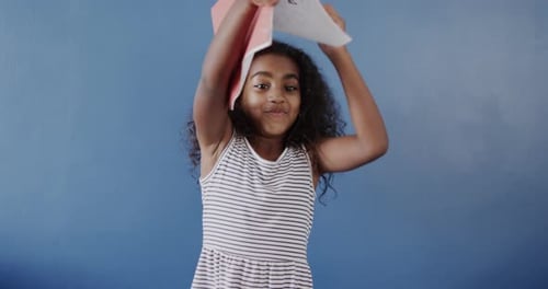 Happy Girl Playing With Book on Blue Background