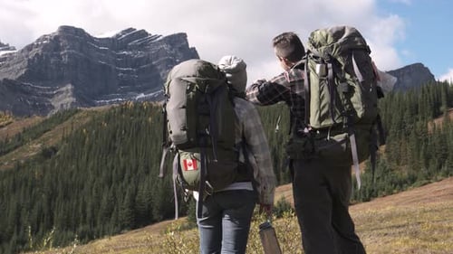 Couple with backpacks enjoying scenic hike in sunny canadian rocky mountains