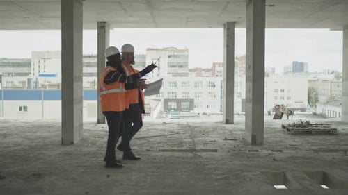 Construction Workers Discussing Blueprints Inside Building