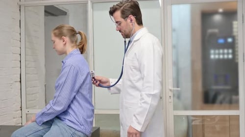 Doctor Listens to Patient Back with Stethoscope in Clinic