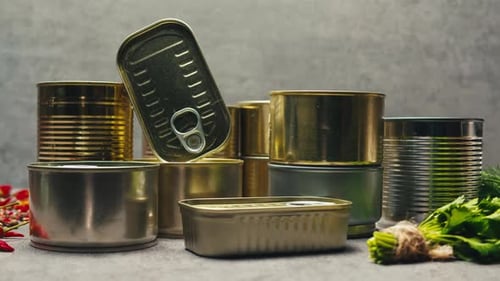 Latas de metal con comida enlatada o paté sobre la mesa, primer plano, latas doradas y plateadas con anillos de tracción enlatadas