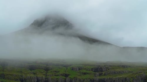 Verdunkelter Berg von dichtem Nebel und Wolken. - Zeitlupe aus der Luft