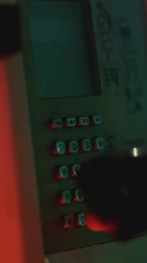 Hand Interacting with Illuminated Keypad in Dimly Lit Setting
